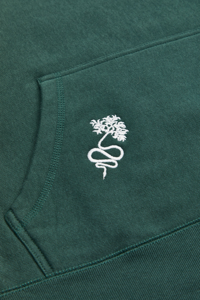 A green or jungle green hoodie with the Lilith NYC wordmark logo embroidered on the upper left chest area. Embroidery of a snake with a branch tail is located on the right side of the kangaroo pocket. All embroidery is in cream or off-white. 
