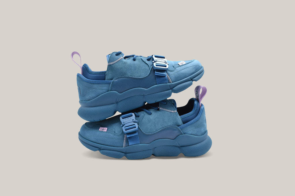 Lateral view of the Kali Blue sneakers. The left shoe is stacked on top of the right shoe.