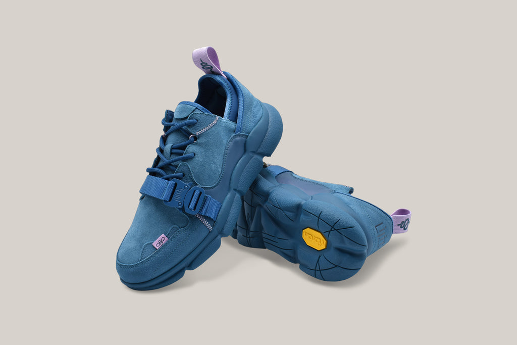 View of the Kali Blue sneakers. The left shoe is stacked on top of the right shoe with the yellow Vibram sole logo in view.